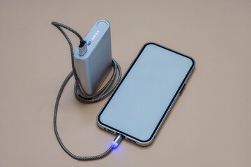 Portable charger charges a smartphone on a light background. Mobile phone mockup with white screen...