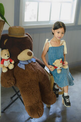 Girl alone happy and enjoy travel in my house with big teddy bear.