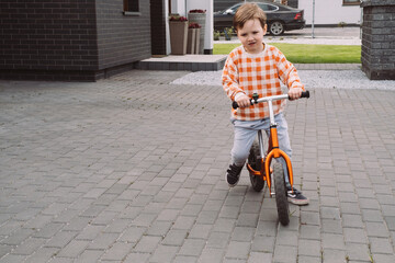 Child playing racing on bike in the home yard. Boy riding fast around private house. Family games competitions. Kids sport activities outdoors near home