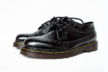 Full black brogue wingtip shoes made of genuine cowhide with a detailed pattern on a white background