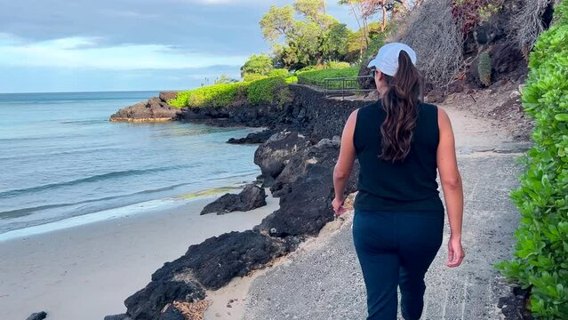 Young Hispanic woman walking along the beach on a walkway in an island paradise