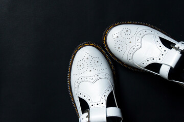 White mary jane shoes made of genuine leather with accurate pattern details on a black background