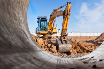 Heavy excavator at the construction site. View of the excavator through the iron pipe. Construction...