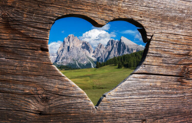 With love from the Dolomites in Italy. Heart shaped view through the bench towards the mountains.  - obrazy, fototapety, plakaty
