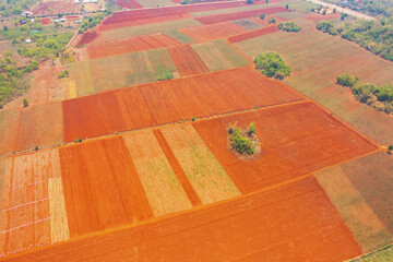 Aerial top view of red soil, crops field with green mountain hill in agriculture concept. Nature landscape background in Thailand. harvest