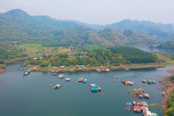 Aerial top view of residential local floating houses in Mon village, nature trees with lake or river, Kanchanaburi, Thailand in urban city town in Asia, buildings.