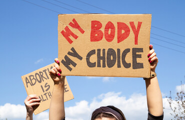 Protesters holding signs My Body My Choice and Abortion Is Healthcare. People with placards...