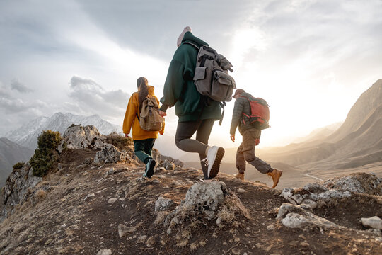 Young hikers with backpacks walks in mountains at sunset