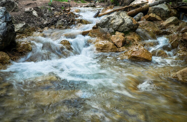 Cascade of waterfalls among stones. Fluffy water. Spring landscape. Falling water.