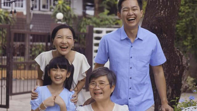 Asian Multi Generational Family Looking At Camera And Smiling At Home. Young Parents Wih Daughter And Grand Mother Together