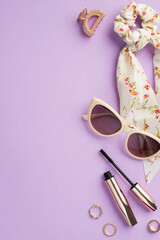 Make up beauty concept. Top view vertical photo of trendy scarf scrunchy mascara sunglasses gold rings and hairpin on isolated purple background