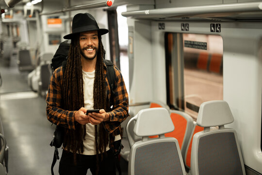 Handsome young man traveling by a train. Urban guy using the phone.