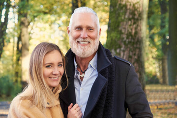 Shot of happy couple of handsome senior man and young blond haired woman in autumn.