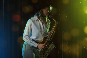 Fototapeta na wymiar Beautiful young woman playing saxophone on dark background. Bokeh effect
