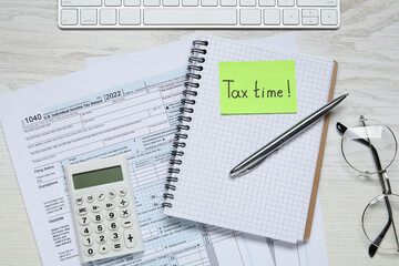 Reminder note with words Tax Time, documents, keyboard, glasses and calculator on white wooden...