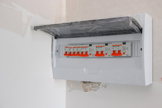 PERM, RUSSIA FEBRUARY 25, 2022: Household energy meter and automatic fuses or circuit breakers in the open wall plastic distribution box. Consumer unit fuse board or electrical control panel