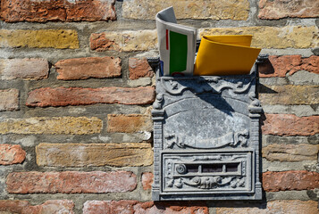 Vintage post box with newspaper and letter on old brick wall. Space for text