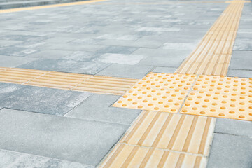 Grey pavement with tactile tiles outdoors. Public environment accessible for visually impaired