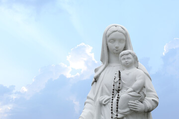 Fototapeta na wymiar Beautiful statue of Virgin Mary and baby Jesus with rosary beads outdoors. Space for text