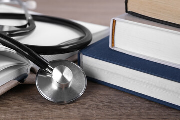 Student textbooks and stethoscope on wooden table, closeup. Medical education - obrazy, fototapety, plakaty