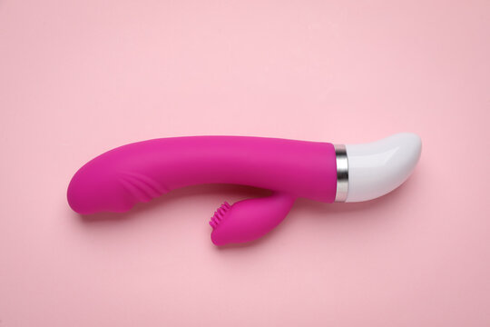 Vaginal vibrator on pink background, top view. Sex toy