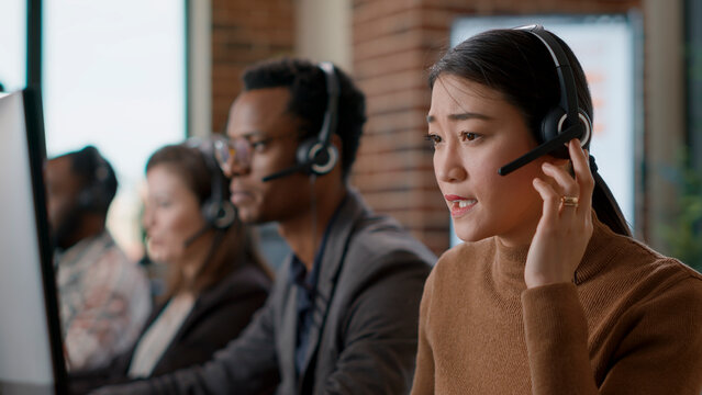 Female sales agent talking on phone call to client, helping people at customer support service. Woman using headphones to give assistance at call center workstation, helpdesk.