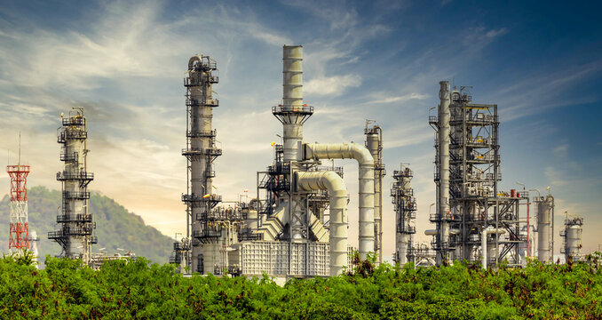 Oil Refinery Plant From Industry Zone, Oil And Gas Petrochemical Industrial With Tree And Blue Sky Background, Refinery Factory Oil Storage Tank And Pipeline Steel, Ecosystem And Healthy Environment.