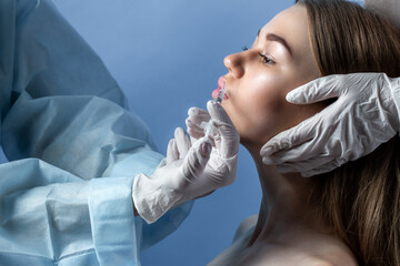 Hands of cosmetologist making injection in face, lips. Young woman gets beauty facial injections in...