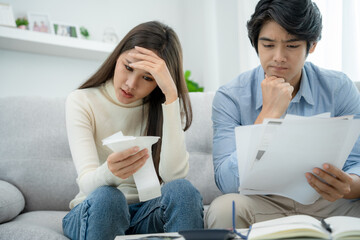 Asian couples are worried about debt and expenses. Stressful women and men receive bank loan invoices. credit card , water, electricity , telephone bills. No money and broke