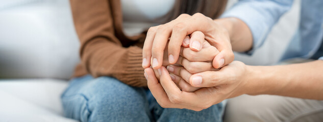 Couples hold hands to support each other while discussing family issues with a psychiatrist. Men...
