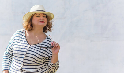 Portrait of attractive plus size mature woman in casual style walk at city at good sunny day and thinking about something. Life of women after 40-50 years