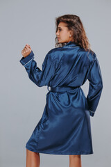 very sexy curly girl in a blue robe, night dress on a gray background. home clothes concept. catalog photo