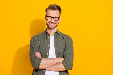 Portrait of attractive cheerful content intellectual guy folded arms isolated over bright yellow...