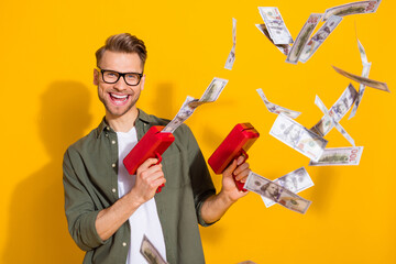 Portrait of attractive trendy cheerful rich guy shooting us money exchange isolated over bright...