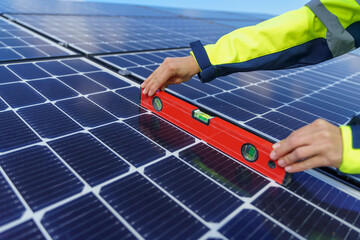 Close-up of woman engineer measuring solar photovoltaic panels on roof, alternative energy concept.