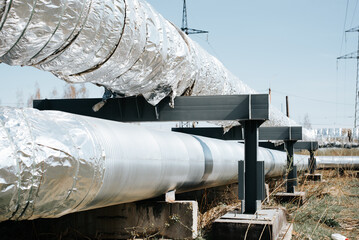 Side view of two pipes with thermal insulation on sunny day outdoors. Large industrial pipeline