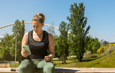 Female athlete is connecting the phone to the headphones.