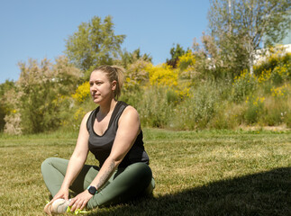 Sportswoman sitting in the meadow, resting