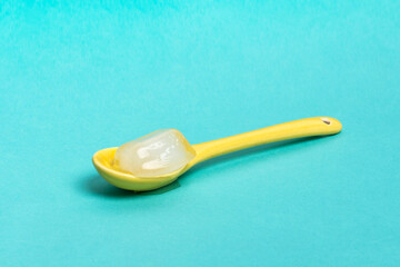 Yellow spoon with ice cube