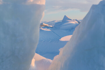 Winter arctic landscape. View of large ice hummocks and snowdrifts. The frozen sea. Cold frosty...