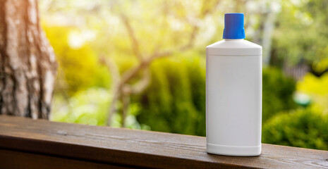 white blank fertilizer bottle on garden background. banner with copy space