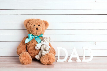 Dad toy bear with baby bear and word Dad on a white wooden background. Father's Day card with copy space.