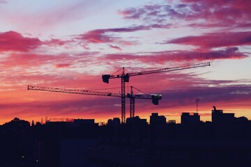 Grúas torre de construcción al atardecer en el barrio de Montecarmelo, Madrid, España. Silueta...