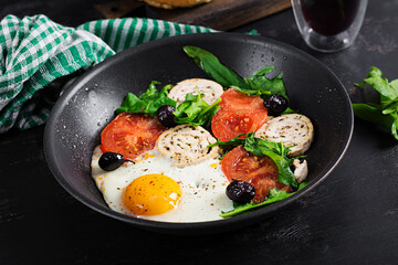 Fried egg, meat roll, black olives,  tomatoes and spinach. Keto breakfast. Ketogenic menu.