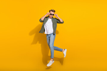Fototapeta na wymiar Full length body size view of attractive cheerful guy jumping touching specs stroll isolated over bright yellow color background