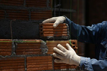 Close up of bricklayer installing bricks on construction site. Concept of repair and building...