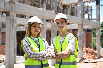 Two architect standing with arm crossed at building construction site.