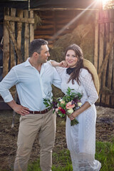 bride in cowboy style sits on threshold of hayloft.Rustic wedding in the style of boho at the ranch
