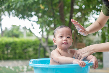 Fototapeta na wymiar 7 month old baby taking a bath in a good mood outdoors