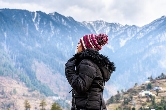 Young woman traveller looking towards the Himalayas mountains in Sainj Valley, Great Himalayan National Park, Himachal